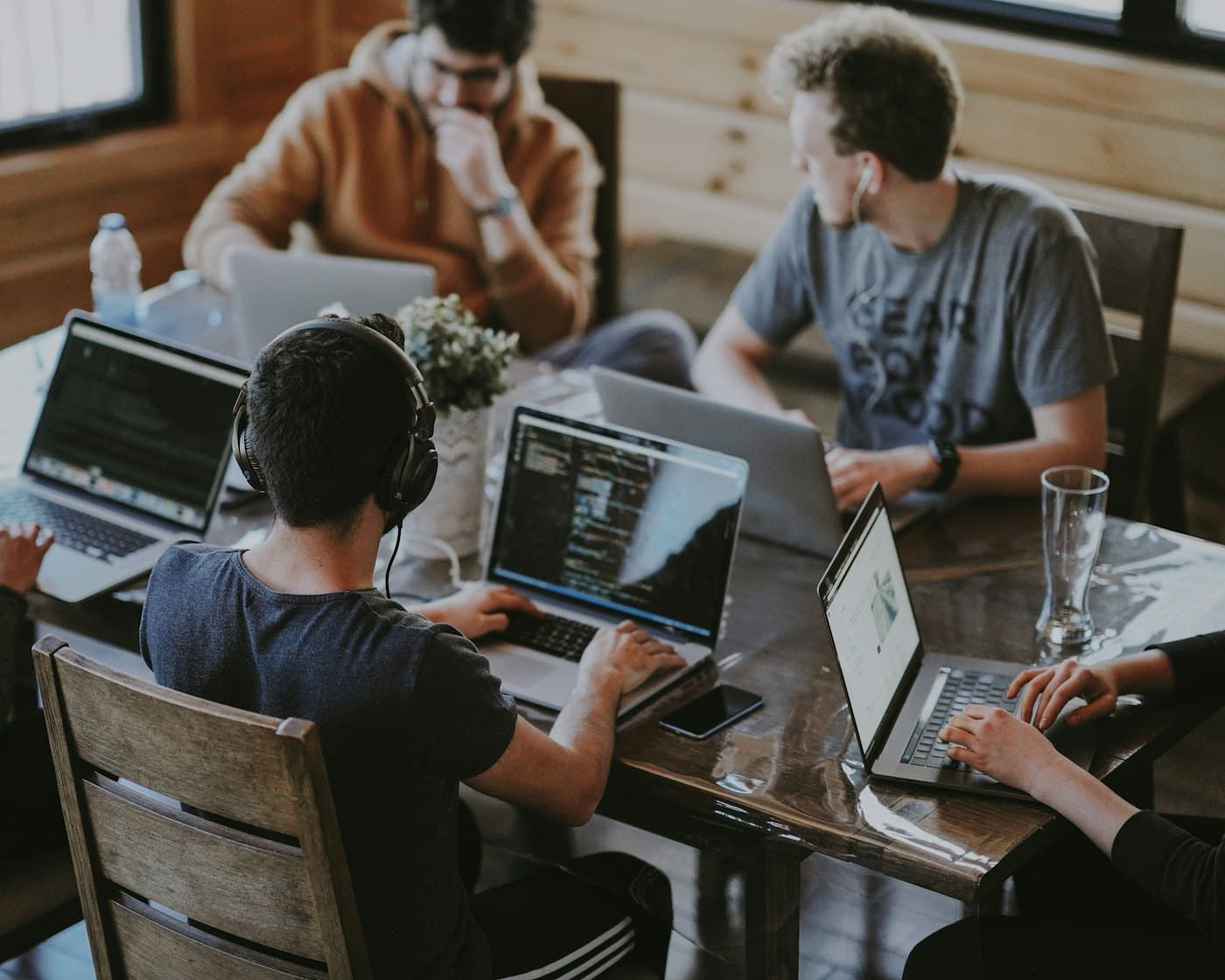 A team of builders working together on laptops around a shared table.